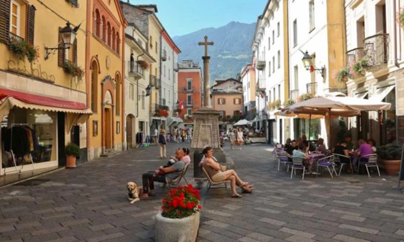 Centro di Aosta con persone sedute sulla panchina, da dove si possono scoprire i castelli e i saperi tipici della Valle d'Aosta