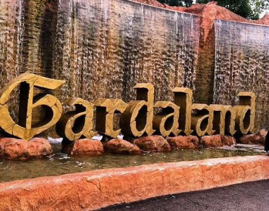 Una giornata a Gardaland. La scritta "Gardaland" all'entrata dell'omonimo parco divertimenti, immersa in una cascata di acqua e rocce di colore rosso mattone