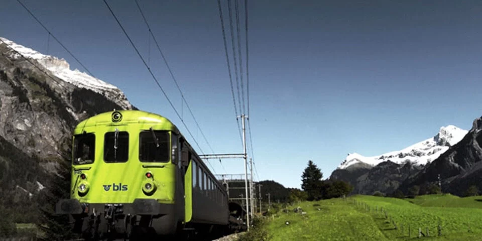 trenino verde delle alpi in viaggio nel mezzo delle montagne e circondato dal verde dei prati, che si dirige verso la festa del vino a Spiez e crociera sul lago di Thun