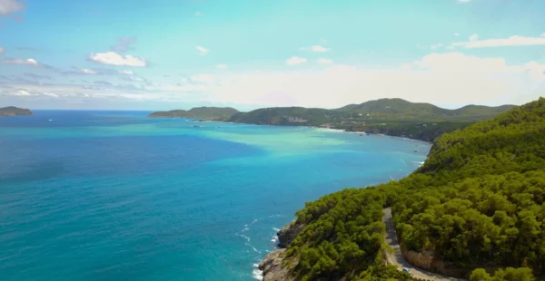 Isola di Minorca, vista dall'alto con mare cristallino e colline verdi che si increspano nel mare, con paesaggio che sembra dipinto Soggiorno baleari minorca